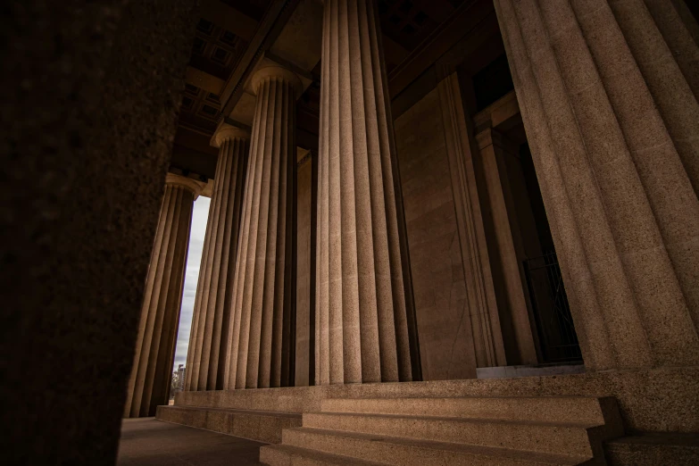 the columns of a building with a clock and street light