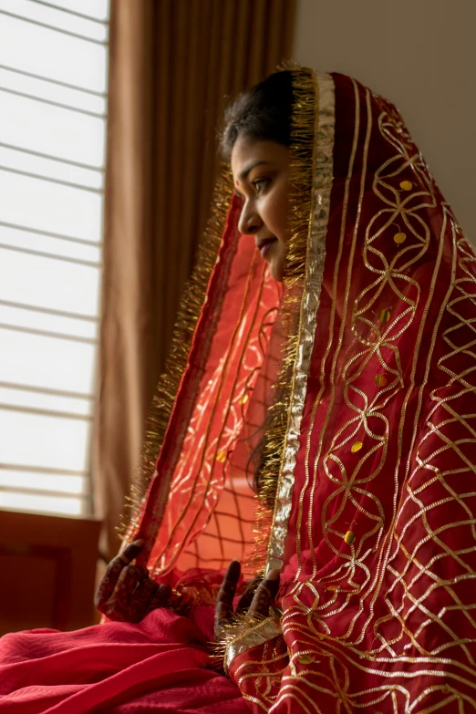 a woman sitting on a bed dressed in red and gold