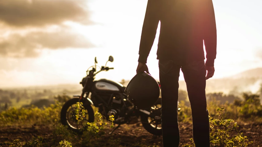 the silhouette of a man standing in front of a motorcycle