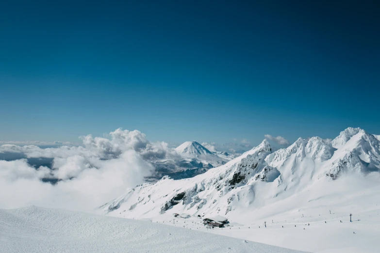 a mountain range with many snow covered mountains and a couple clouds