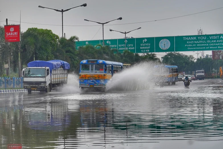 a flooded street with cars and buses being driven by water