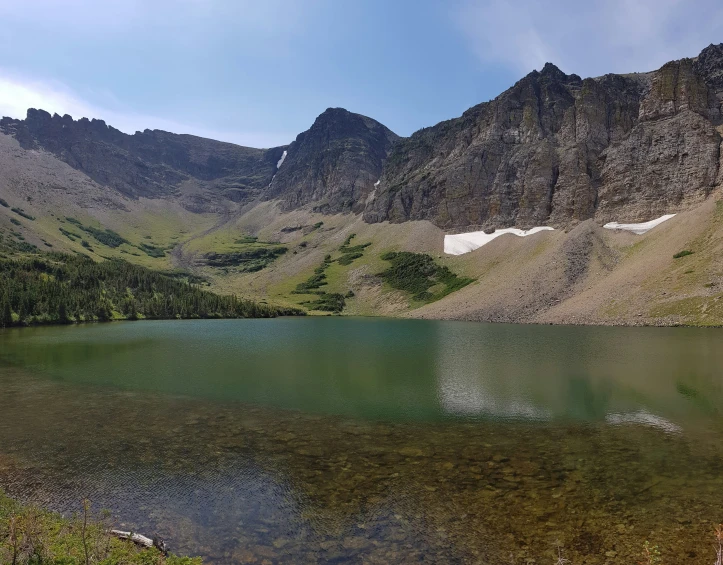 an alpine landscape with a lake and snow capped mountains