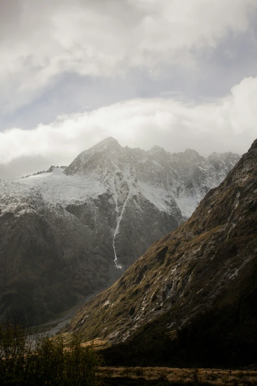 a mountain range covered in snow on a cloudy day