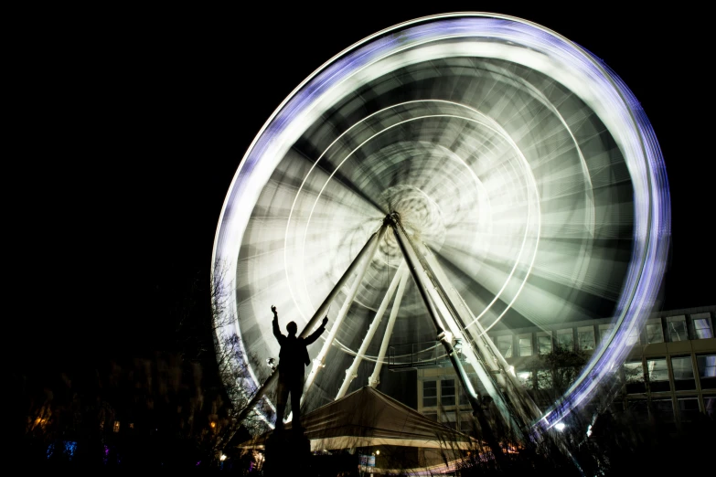 the man is standing up by the ferris wheel