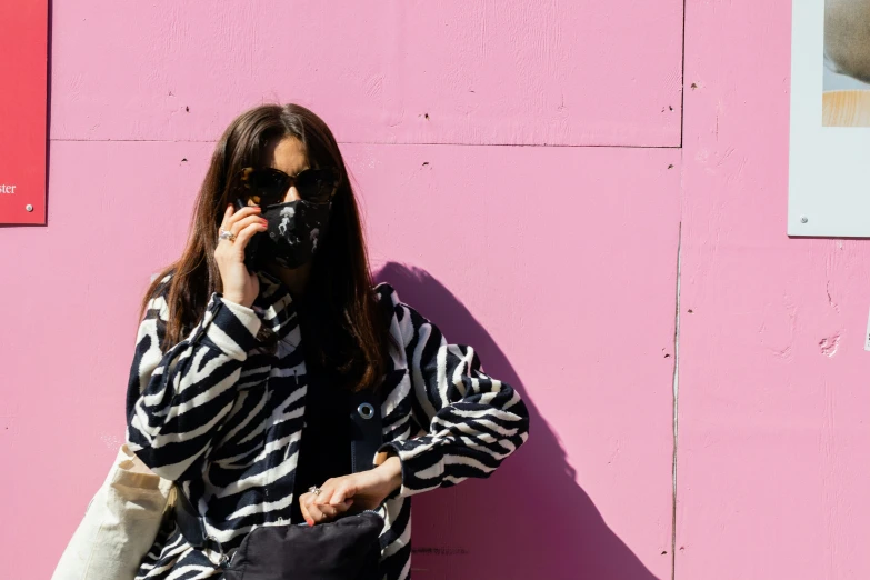 a woman holding a black purse talking on a cell phone