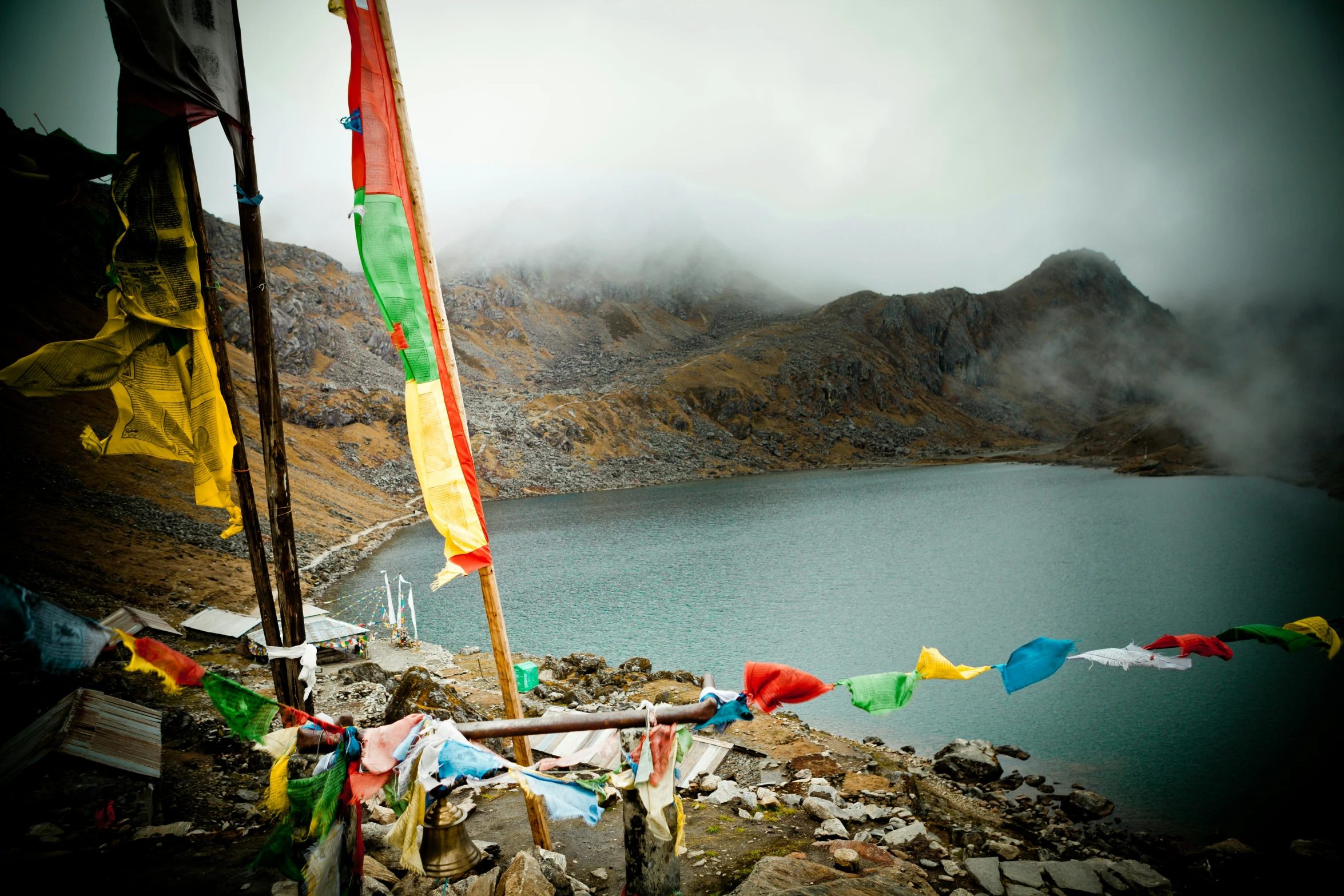 flags with rainbow colors are hanging on the rocks near water