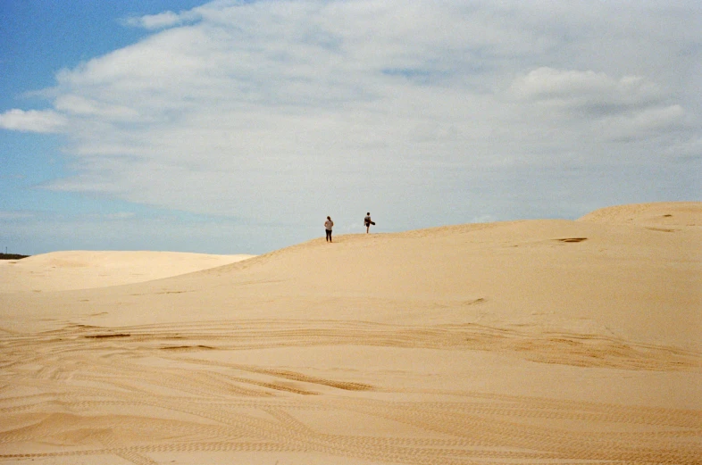 two people on top of a sandy hill