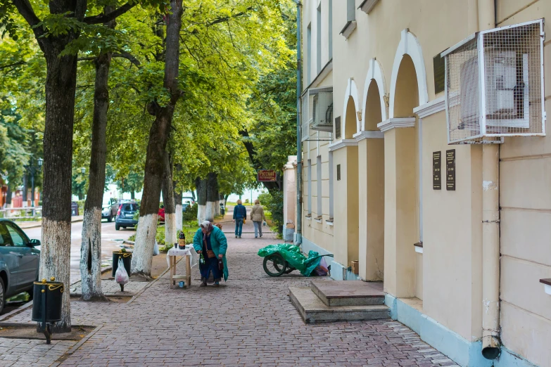 people walking on a sidewalk by some shops