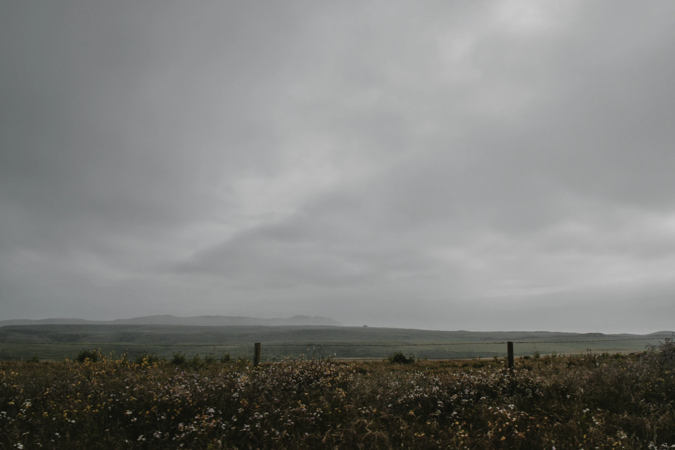 a dark cloudy sky above an open field