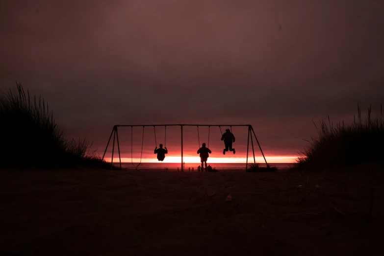 a couple playing on a swing set in the dark
