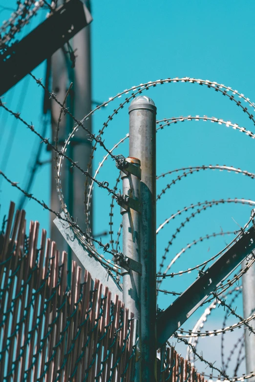 several razor razors on a steel post and behind a barbed wire fence