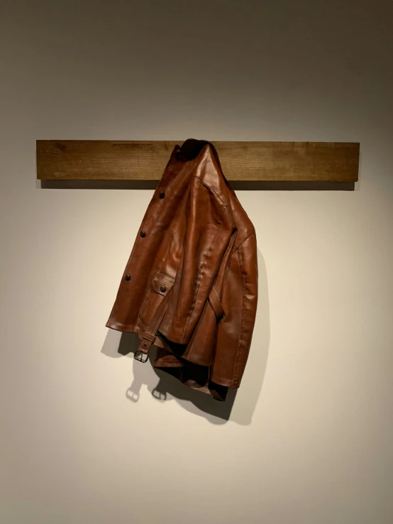 a brown leather coat hangs on the wall