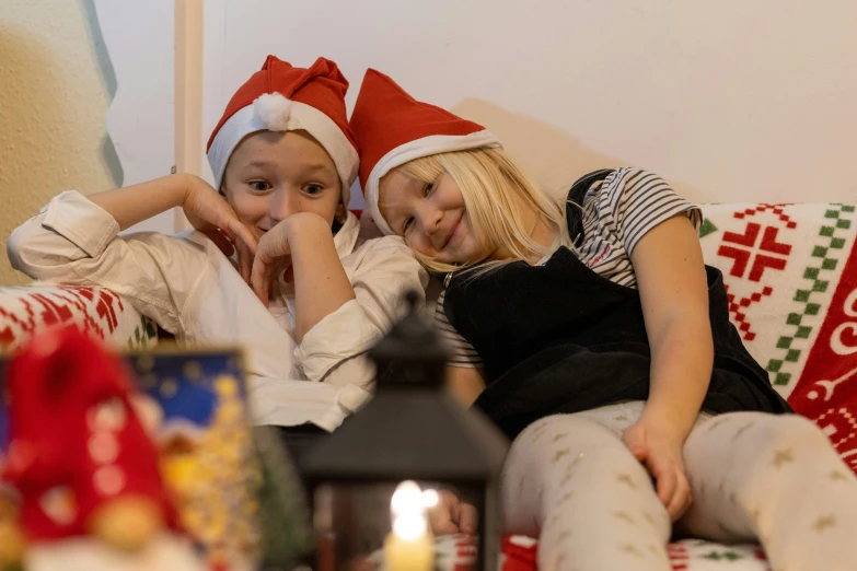 two girls sitting on a couch near a christmas tree