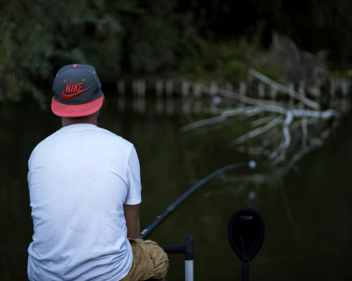 a man sitting on the edge of the water fishing