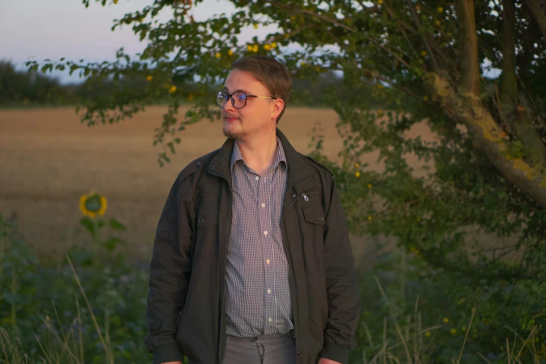 the man in the plaid shirt stands in front of a sunflower