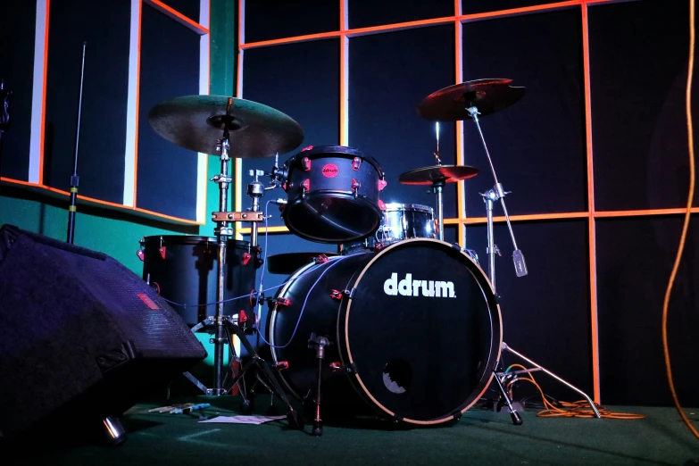 drums sit in front of an orange and blue neon light