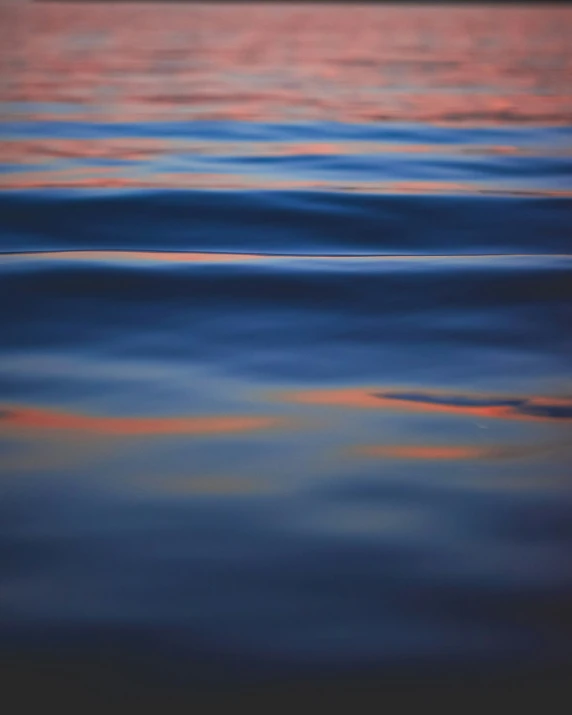 bright orange and blue clouds reflect on the calm water