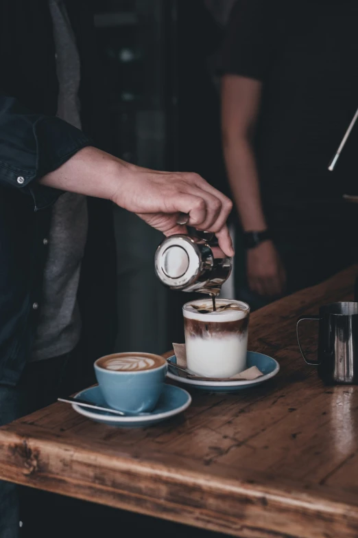 a man pours coffee into two cups on a table