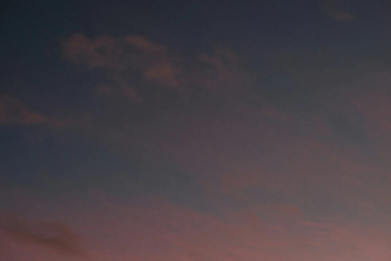 the silhouette of some clouds in the night sky