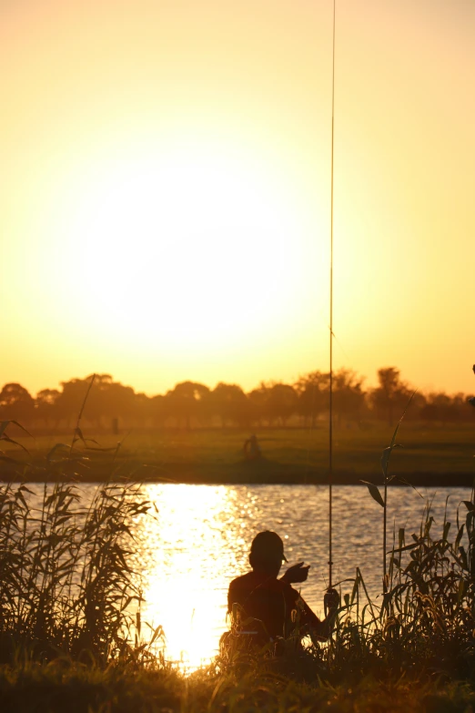 two men fishing at sunset near a lake