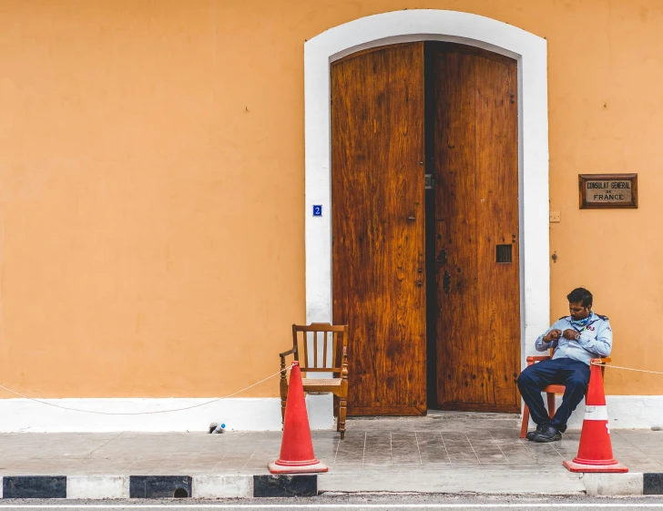 a man sitting at the end of an orange barricade