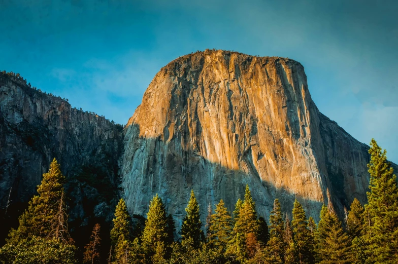 a tall mountain with a cluster of trees near by