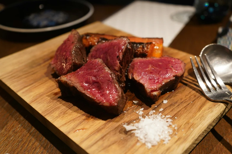 a wooden  board topped with slices of beef