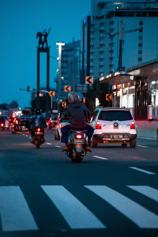 three motorcycles are traveling in the traffic while the man sits on the car waiting for the signal