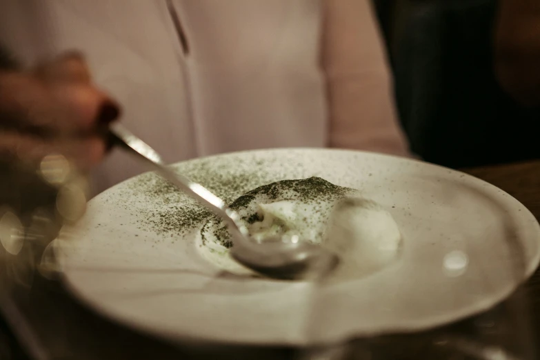 spoon with food in white dish sitting on table