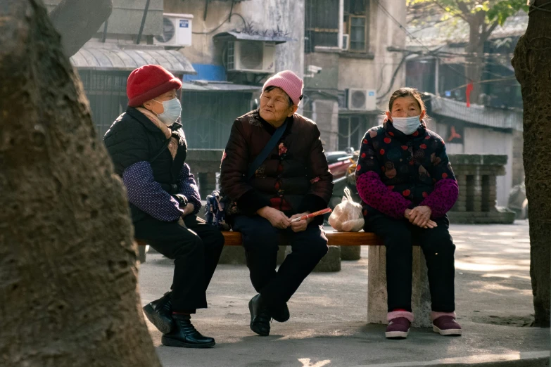 three women sitting on a bench in the middle of a city