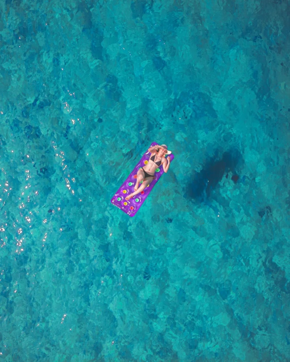 the woman is on the blue water on a purple tube