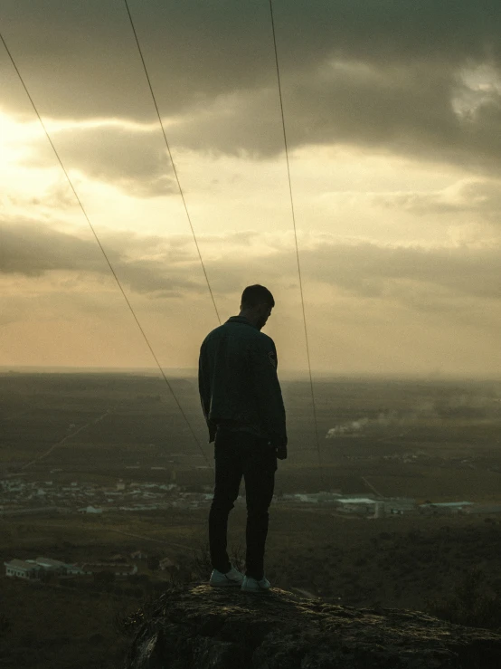 a man is standing at the top of a mountain looking at the sky