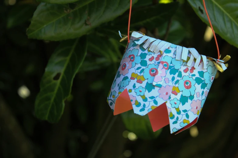 a small colorful decoration hangs from the top of a tree