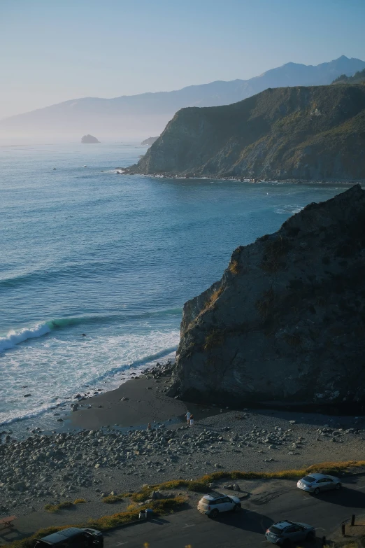 a beach next to the ocean with lots of cars parked