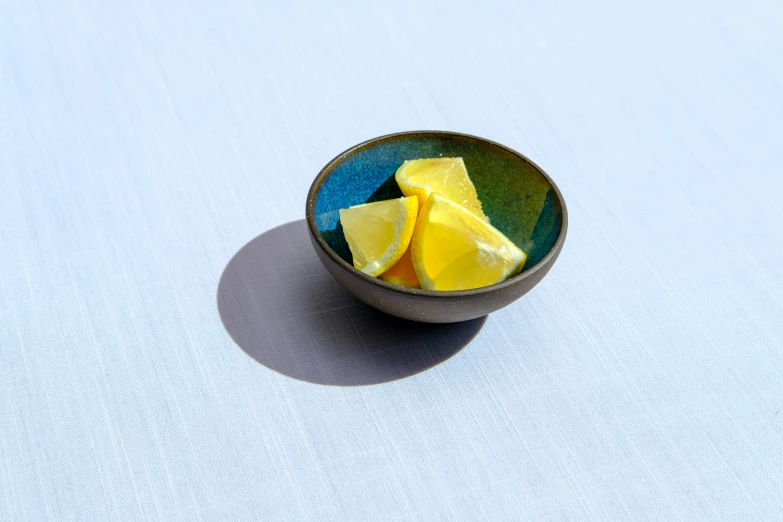 a blue bowl with cut lemons and water