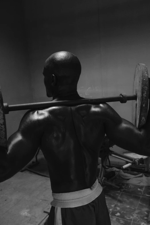 a man wearing black and white has his back to the camera while holding a barbell