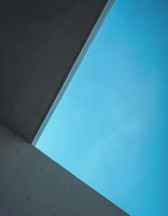 the bottom of a concrete building with a blue sky above it