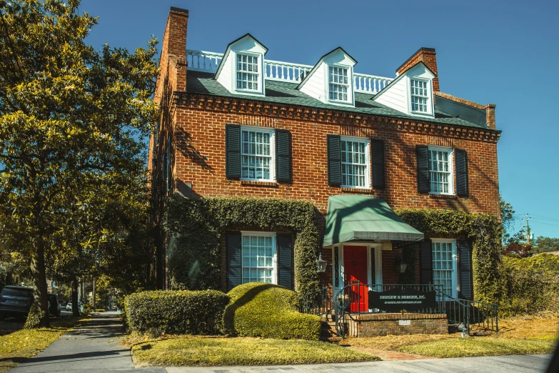 a large red brick building with shutters and some bushes on the side