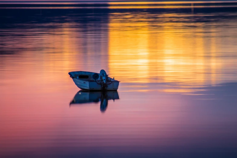 small white boat sitting in the middle of a body of water