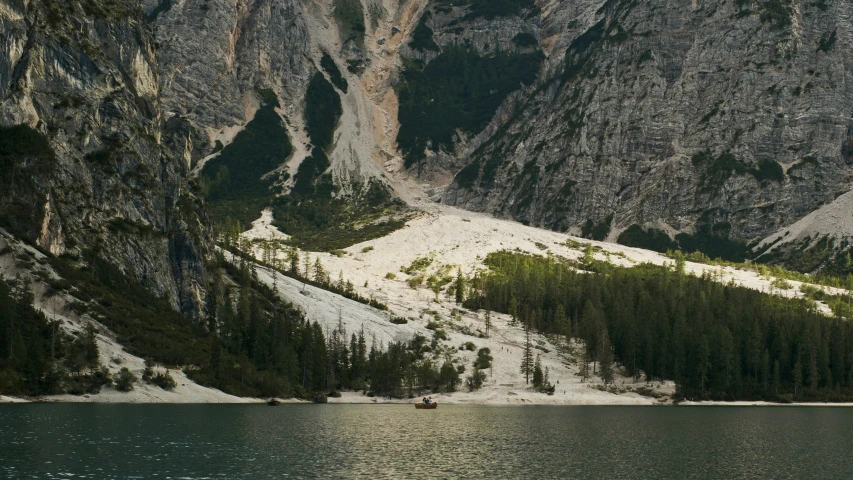 a snowy mountain landscape with trees and boats on the water