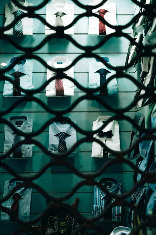 some shirts hanging on the wall behind a metal fence