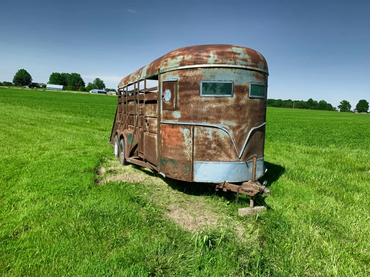 a rusty old truck sitting in the middle of a field