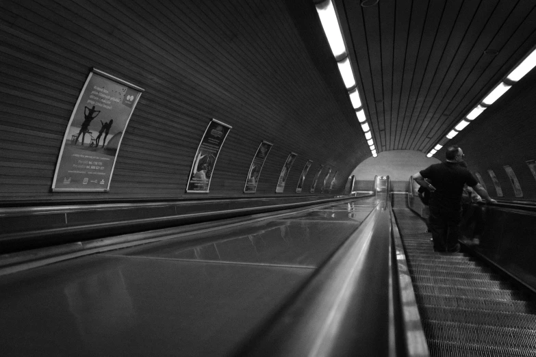 a man riding an escalator down the aisle in black and white