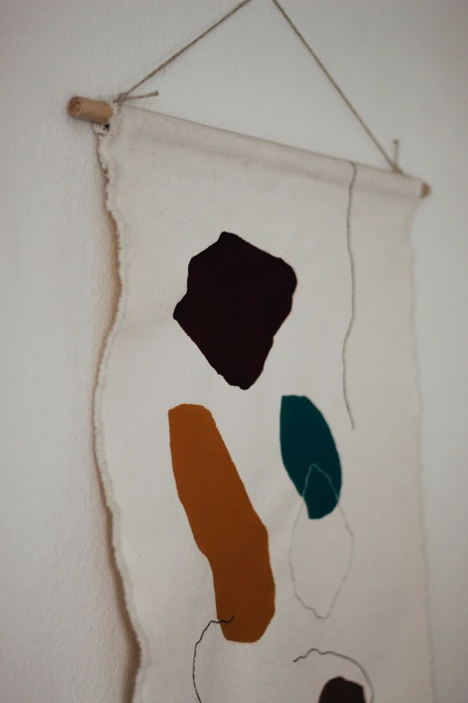 a wall hanging with a white background and various color shapes