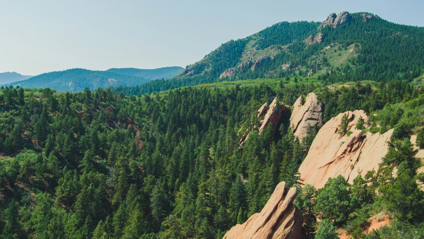 a large rock cliff surrounded by trees and mountains