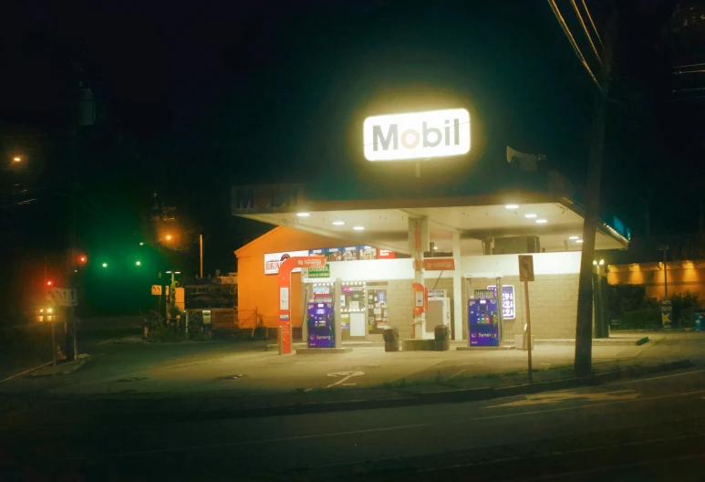 an oil station is shown at night near some traffic lights