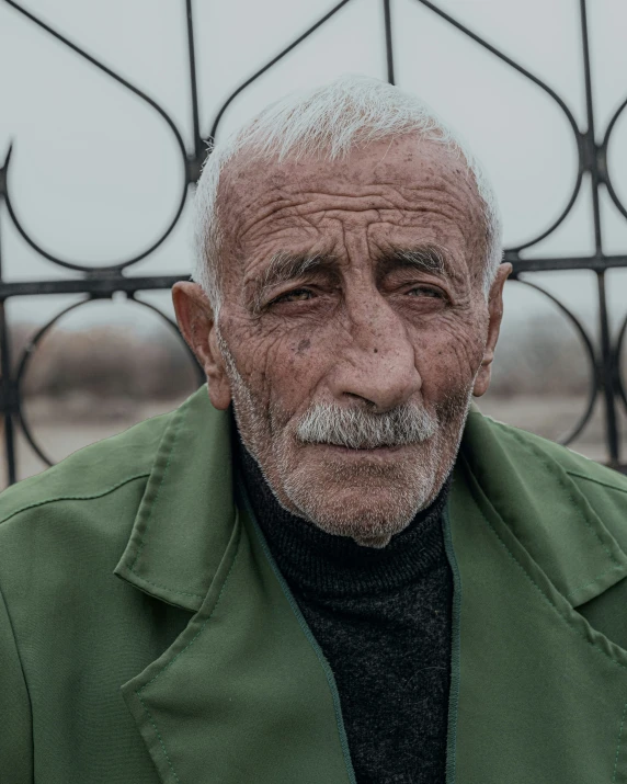 an old man with white hair and green jacket on