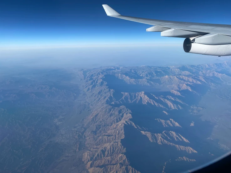 the wing of a passenger plane over a mountain range