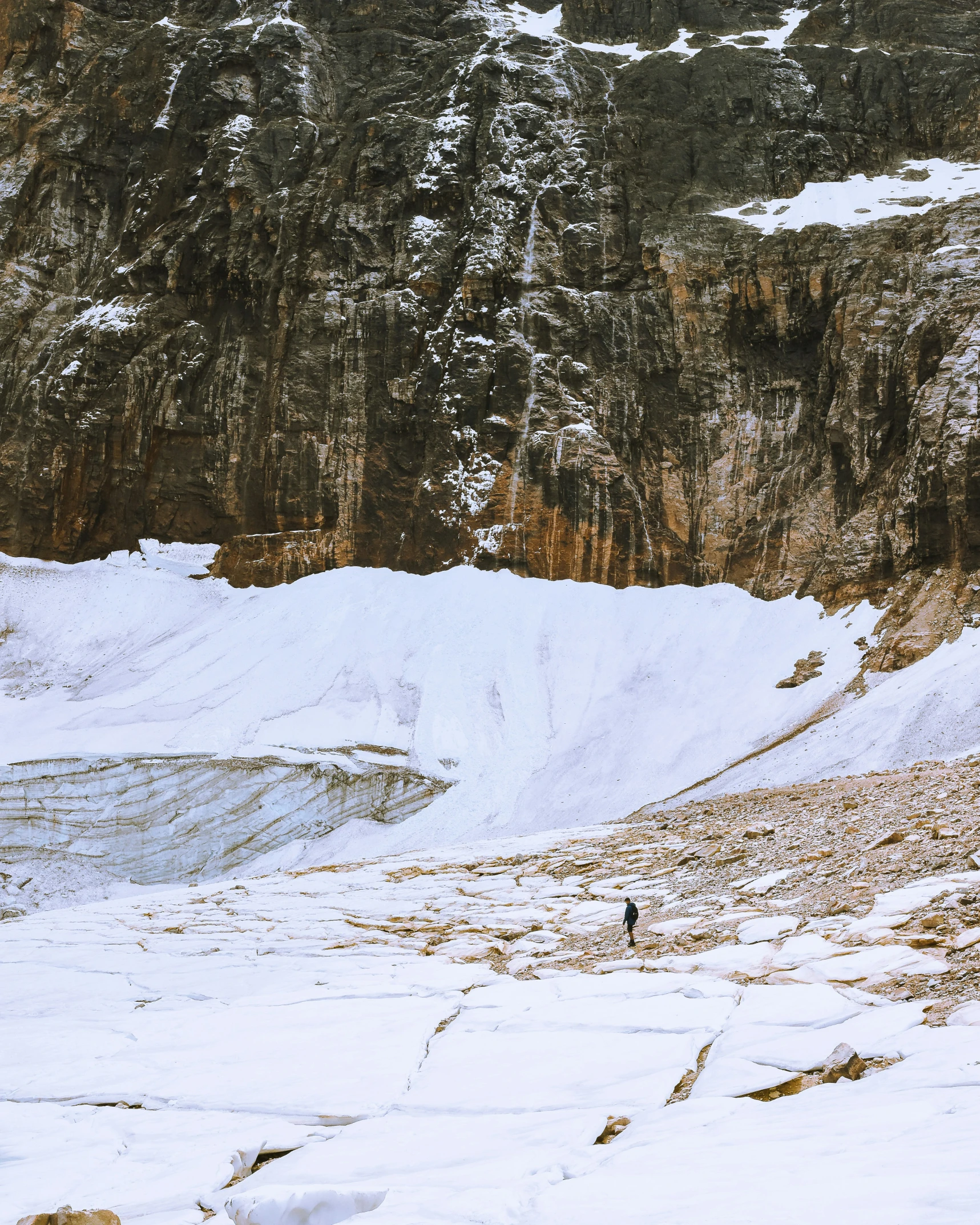 two people standing on snow covered ground with snow covered mountains in the background