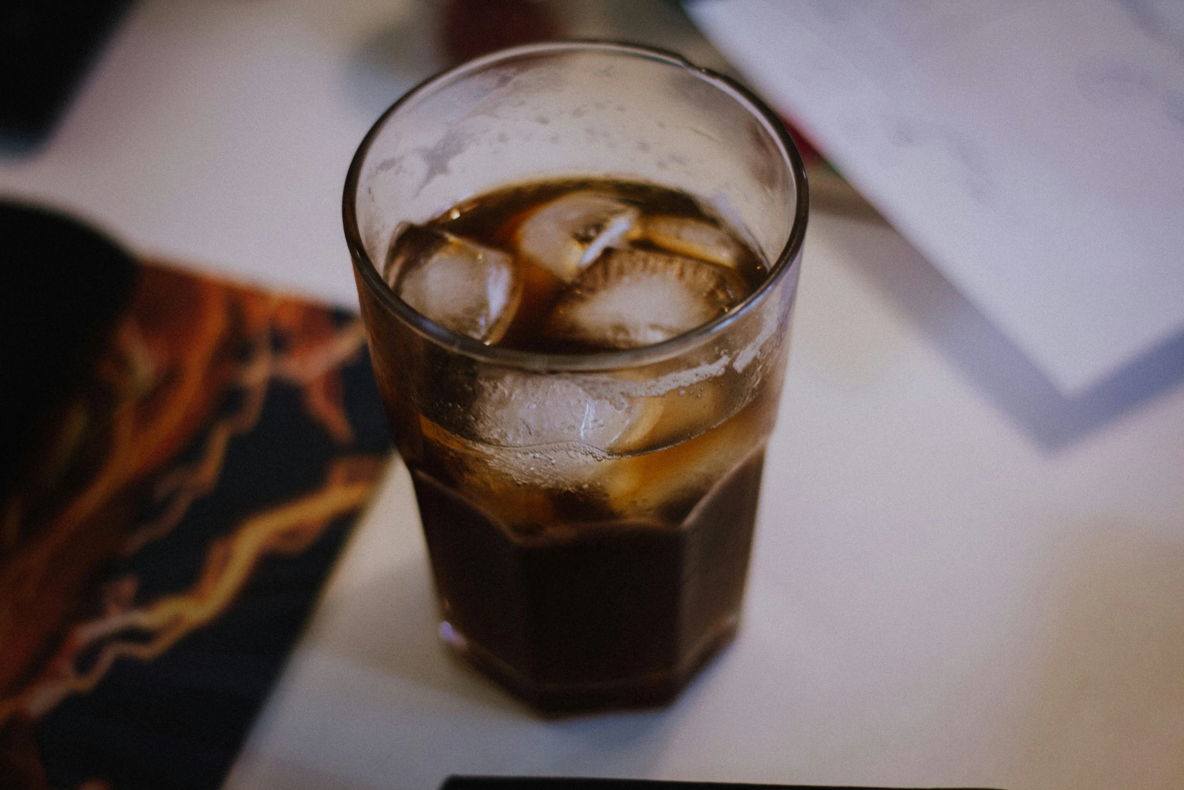 a glass of soda with ice and straw on a table